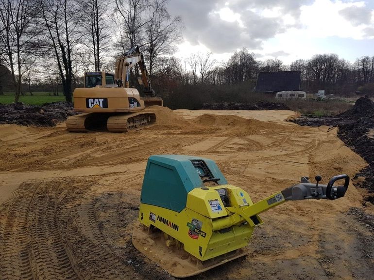 Baustelle mit Caterpillar Bagger und Ammann Rüttelplatte