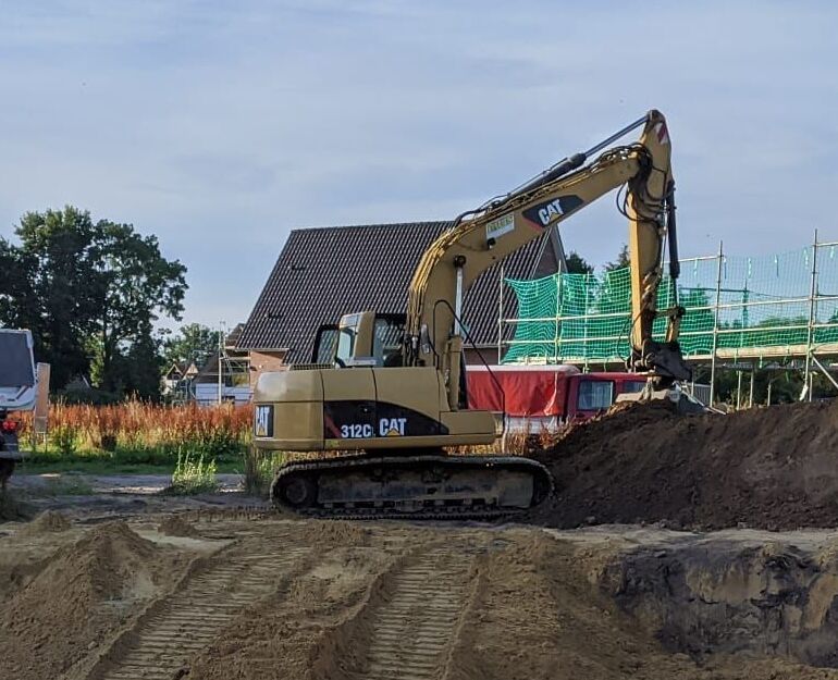 Gelber CAT 312C Bagger auf einer Baustelle mit Erde